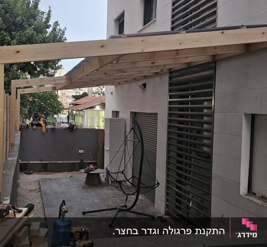בניית פרגולה מעץ ליד בניין מגורים